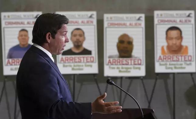Posters of alleged criminals who officials said were arrested in a recent immigration enforcement operation are displayed as Gov. Ron DeSantis speaks during a press conference at the South Florida office of U.S. Immigration and Customs Enforcement and Enforcement and Removal Operations, Thursday, May 1, 2025, in Miramar, Fla. (AP Photo/Rebecca Blackwell)