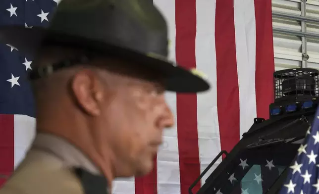 A member of the Florida Highway Patrol listens during a press conference on a recent immigration enforcement operation, with Gov. Ron DeSantis at the South Florida office of U.S. Immigration and Customs Enforcement and Enforcement and Removal Operations, Thursday, May 1, 2025, in Miramar, Fla. (AP Photo/Rebecca Blackwell)