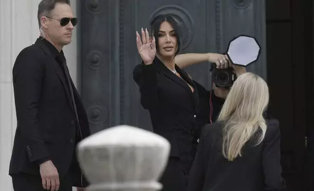 Kim Kardashian waves as she arrives to testify regarding a robbery of millions of dollars in jewels from her Paris hotel room in 2016, in Paris, Tuesday, May 13, 2025. (AP Photo/Aurelien Morissard)