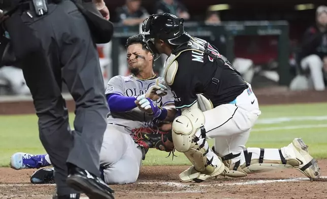Arizona Diamondbacks catcher Gabriel Moreno, right, tags out Colorado Rockies' Ezequiel Tovar at home plate during the ninth inning of a baseball game Saturday, May 17, 2025, in Phoenix. (AP Photo/Ross D. Franklin)