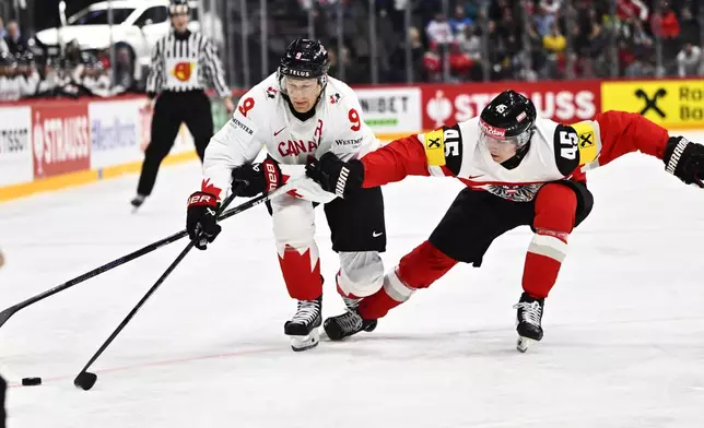 Canada's Nate MacKinnon, left, and Austria's Gregor Biber, right, challenge for the puck during the IIHF Ice Hockey World Championship group A match between Canada and Austria in Stockholm, Sweden, Thursday, May 15, 2025. (Anders Wiklund/TT News Agency via AP)