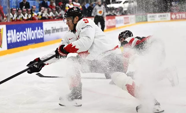 Canada's Nate MacKinnon, left, and Austria's Gregor Biber, right, challenge for the puck during the IIHF Ice Hockey World Championship group A match between Canada and Austria in Stockholm, Sweden, Thursday, May 15, 2025. (Anders Wiklund/TT News Agency via AP)