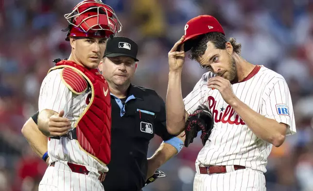 Philadelphia Phillies starting pitcher Aaron Nola, right, waits for a new PitchCom as catcher J.T. Realmuto, left, looks on during the fifth inning of a baseball game against the Arizona Diamondbacks, Saturday, May 3, 2025, in Philadelphia. (AP Photo/Chris Szagola)