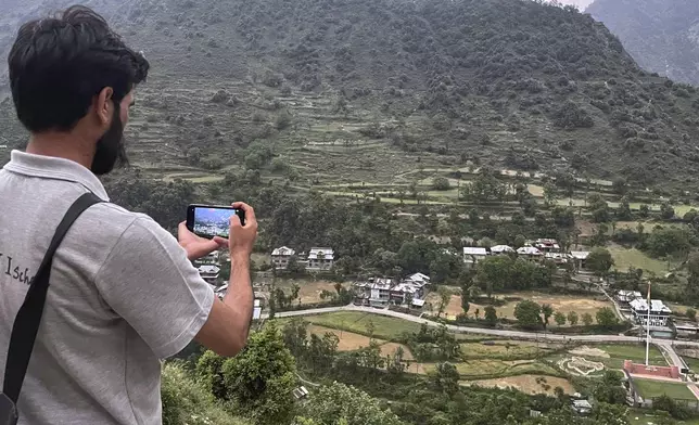 A local resident takes pictures with his mobile phone of Indian side Kashmir, at a view point from Pakistan side on the Line of Control, the de facto border dividing Pakistan and Indian Kashmir, in Chilhana, some 45 kilometres (27 miles) from Muzaffarabad, the capital of Pakistan controlled Kashmir, Thursday, May 1, 2025. (AP Photo/M.D. Mughal)