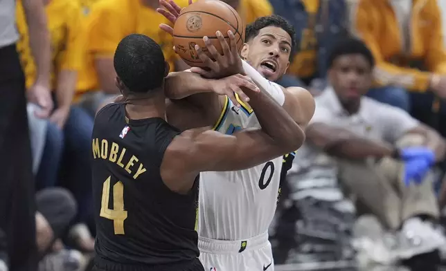 Indiana Pacers guard Tyrese Haliburton (0) and Cleveland Cavaliers center Evan Mobley (4) battle for the ball during the first half of Game 3 in the Eastern Conference semifinals of the NBA basketball playoffs in Indianapolis, Friday, May 9, 2025. (AP Photo/Michael Conroy)