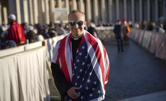 Ethan Menning, 21, from Omaha, Nebraska, is wrapped in a flag of the United States as he arrives to attend Pope Leo XIV's formal inauguration of his pontificate with a Mass in St. Peter's Square attended by heads of state, royalty and ordinary faithful, Sunday, May 18, 2025. (AP Photo/Andrew Medichini)