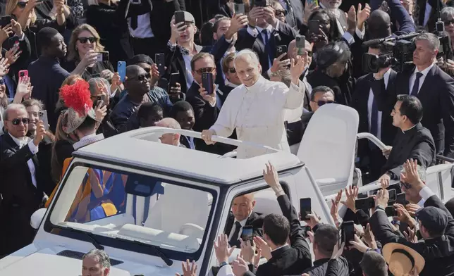 Pope Leo XIV waves from aboard the popemobile as he is driven through the crowd for the formal inauguration of his pontificate with a Mass in St. Peter's Square attended by heads of state, royalty and ordinary faithful, Sunday, May 18, 2025. (AP Photo/Stefano Costantino)