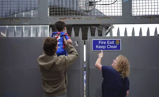 Crystal Palace fans try to sneak a peak inside Selhurst Park before the FA Cup winners parade in London, Monday, May 26, 2025. (Yui Mok/PA via AP)