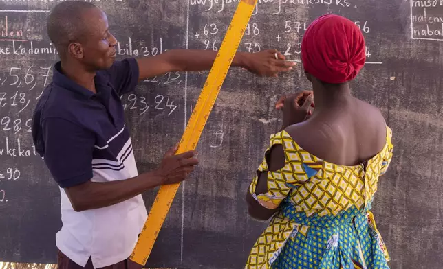 Sidi Yaya Sangare, left, teaches Bambara in a makeshift classroom in the village of Mountougoula, Mali, April 7, 2025. (AP Photo/Saydou Camara)