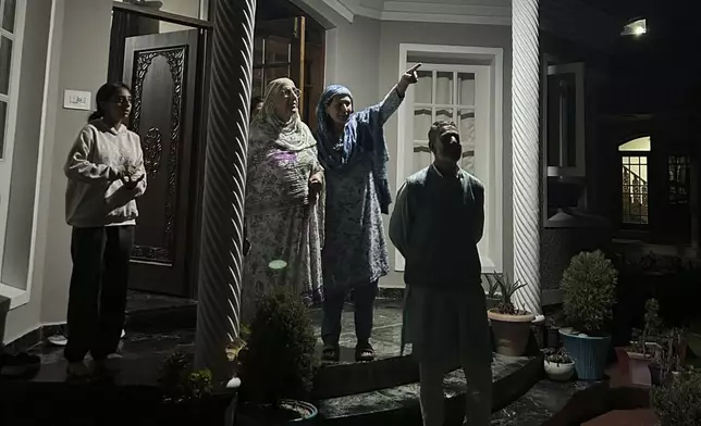 A Kashmiri family watches towards the sky as projectiles fly over the sky in Indian controlled Kashmir, Saturday, May 10, 2025. (AP Photo/Rafiq Maqbool)