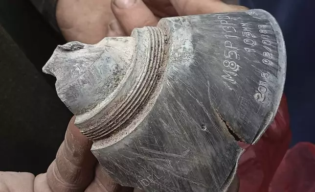 A local resident shows a piece of shell fired by Indian forces, at his damaged house in Haveli Kahuta, a district of Pakistan's administered Kashmir, Friday, May 9, 2025. (AP Photo/Rashid Ahmed)