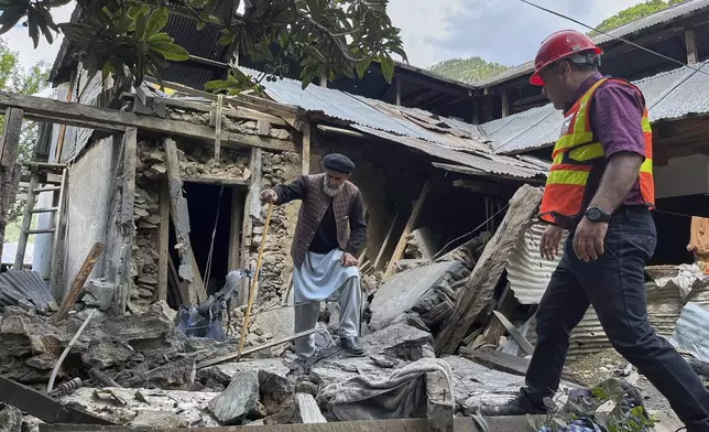 A Kashmiri villager and a rescue worker examine damages to a house caused by overnight Indian shelling, in Shah Kot, in Neelum Vallery, a district of Pakistan's administered Kashmir, Saturday, May 10, 2025. (AP Photo/M.D. Mughal)