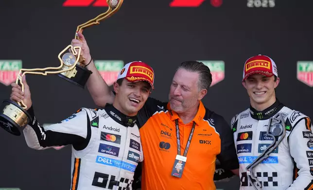 McLaren driver Lando Norris of Britain, left, celebrates on the podium with Zak Brown, McLaren chief, centre, and McLaren driver Oscar Piastri of Australia after winning the Formula One Monaco Grand Prix race at the Monaco racetrack in Monaco, Sunday, May 25, 2025. (AP Photo/Manu Fernandez)