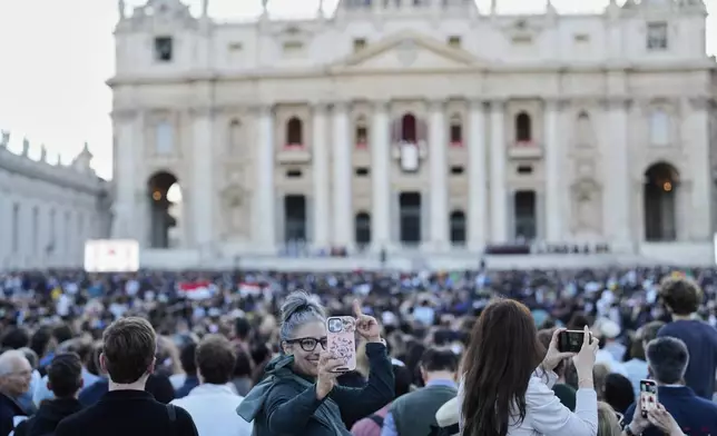 People watch the newly elected Pope Leo XIV as he appears at the balcony of St. Peter's Basilica at the Vatican, Thursday, May 8, 2025. (AP Photo/Bernat Armangue)