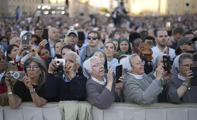 People listen the speech of the newly elected Pope Leo XIV at the Vatican, Thursday, May 8, 2025. (AP Photo/Francisco Seco)