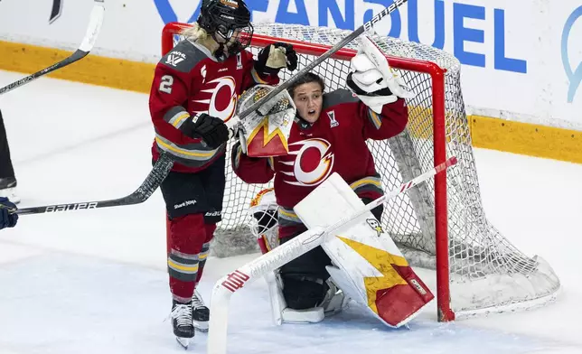 Ottawa Charge goaltender Gwyneth Philips, right, reacts after losing her helmet during third-period PWHL hockey playoff action against the Montreal Victoire in Ottawa, Ontario, Friday, May 16, 2025. (Spencer Colby/The Canadian Press via AP)