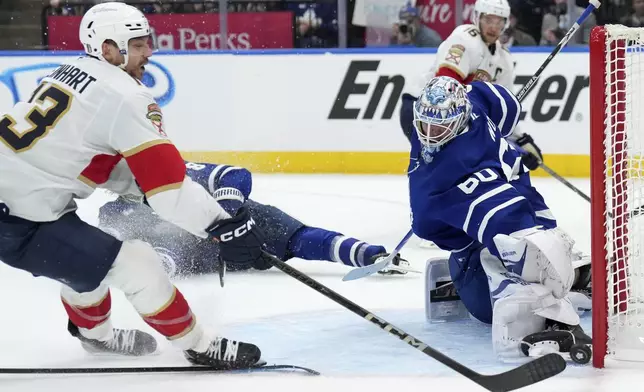 Toronto Maple Leafs goaltender Joseph Woll, front right, makes a save against Florida Panthers forward Sam Reinhart, left, during the third period of Game 1 in an NHL hockey second-round playoff series in Toronto, Monday, May 5, 2025. (Nathan Denette/The Canadian Press via AP)