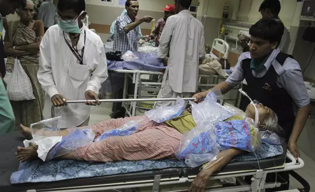 FILE - People wheel in a heat stroke patient, covered in ice cube bags, at a hospital in Ahmadabad, India, May 21, 2010. (AP Photo/Ajit Solanki, File)