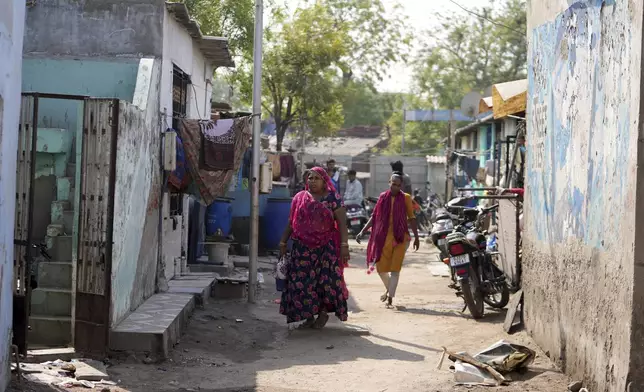 People walk through buildings in Vanzara Vas, a low-income neighborhood, in Ahmedabad, India, Wednesday, April 2, 2025. (AP Photo/Ajit Solanki)