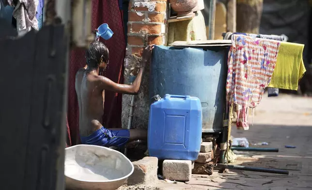 A youth bathes outside his home amid high temperatures in Ahmedabad, India, Wednesday, April 2, 2025. (AP Photo/Ajit Solanki)