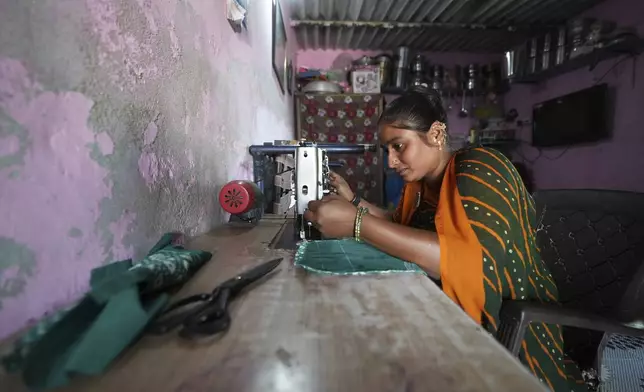Sapnaben Chunara works on a sewing machine inside her house in Ahmedabad, India, Wednesday, April 2, 2025. (AP Photo/Ajit Solanki)