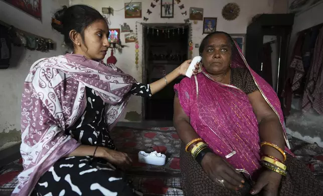 Field data collector Manisha Parmar, left, checks the temperature of Shantaben Vanzara in Ahmedabad, India, Wednesday, April 2, 2025. (AP Photo/Ajit Solanki)