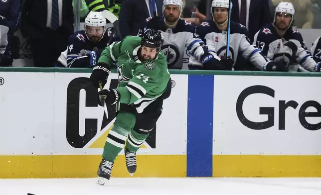 Dallas Stars' Jamie Benn shoots as the Winnipeg Jets bench looks on in the third period of Game 6 of a second-round NHL hockey playoff series in Dallas, Saturday, May 17, 2025. (AP Photo/Gareth Patterson)