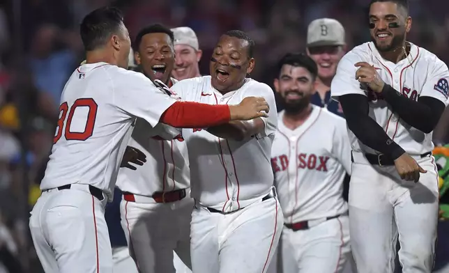 Boston Red Sox's Rafael Devers, center, celebrates with teammates as he scores after hitting a walkoff home run in the ninth inning of a baseball game against the Atlanta Braves, Saturday, May 17, 2025, in Boston. (AP Photo/Steven Senne)