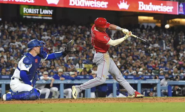 Los Angeles Angels' Logan O'Hoppe, hits a three-run home run as Los Angeles Dodgers catcher Dalton Rushing watches during the seventh inning of a baseball game Saturday, May 17, 2025, in Los Angeles. (AP Photo/Mark J. Terrill)