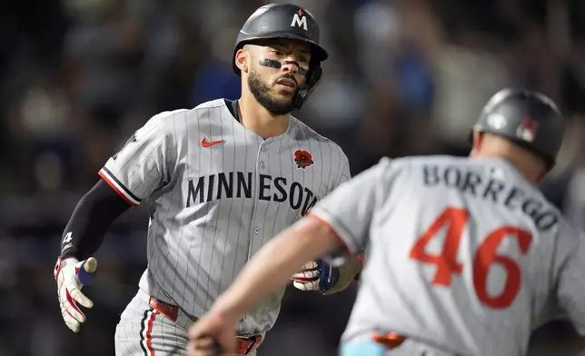 Minnesota Twins' Carlos Correa celebrates his two-run home run off Tampa Bay Rays pitcher Garrett Cleavinger with first base coach Ramon Borrego (46) during the seventh inning of a baseball game Monday, May 26, 2025, in Tampa, Fla. (AP Photo/Chris O'Meara)