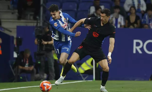 Espanyol's Antoniu Roca, left, is challenged by Barcelona's Robert Lewandowski during a Spanish La Liga soccer match between Barcelona and Espanyol at Lluis Companys Olympic Stadium in Barcelona, Spain, Thursday, May 15, 2025. (AP Photo/Joan Monfort)