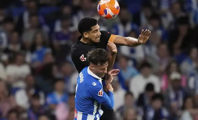 Barcelona's Ronald Araujo, top, and Espanyol's Javi Puado jump for the ball during a Spanish La Liga soccer match between Espanyol and Barcelona in Barcelona, Spain, Thursday, May 15, 2025. (AP Photo/Jose Breton)