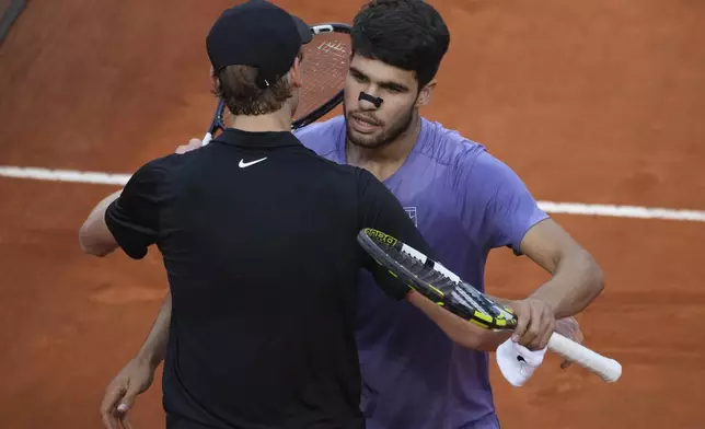 Carlos Alcaraz of Spain, back, embraces Jannik Sinner of Italy during their final tennis match in the Italian Open at the Foro Italico in Rome, Sunday, May 18, 2025. (AP Photo/Andrew Medichini)