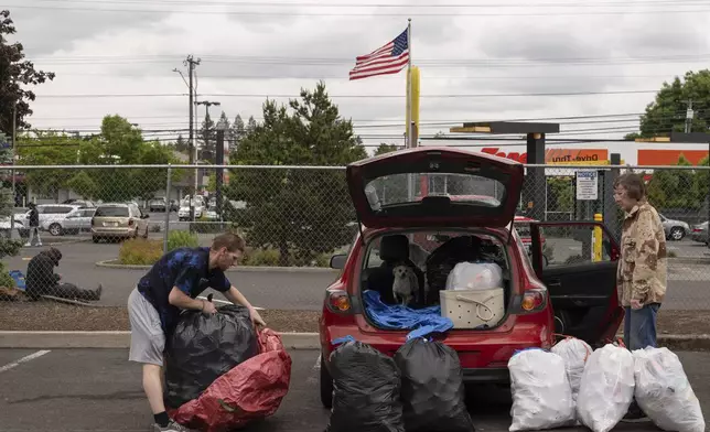 Chris Grass, left, and his father Todd Grass, right, prepare to take over 1,000 used beverage containers inside the Glisan BottleDrop Redemption Center on Thursday, May 15, 2025, in Portland, Ore. (AP Photo/Jenny Kane)