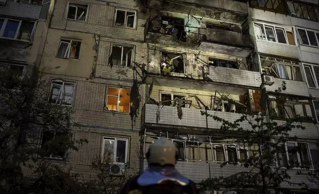 Emergency workers navigates his colleagues at the site of residential building damaged after a Russian attack in Kyiv, Ukraine, Saturday, May 24, 2025. (AP Photo/Alex Babenko)
