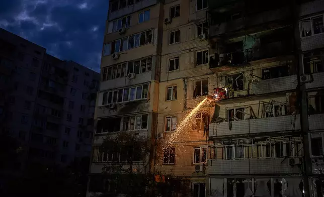 Firefighter clear debris from a balcony at a residential building damaged after a Russian attack in Kyiv, Ukraine, Saturday, May 24, 2025 (AP Photo/Alex Babenko)