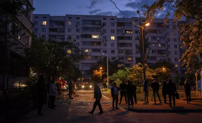 Local residents walk on a street with pieces of broken glass at the site of a residential building that was damaged after a Russian attack in Kyiv, Ukraine, Saturday, May 24, 2025. (AP Photo/Alex Babenko)