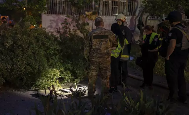 Police officers investigate fragments of a Russian drone at the site of a residential building damaged after a Russian attack in Kyiv, Ukraine, Saturday, May 24, 2025. (AP Photo/Alex Babenko)