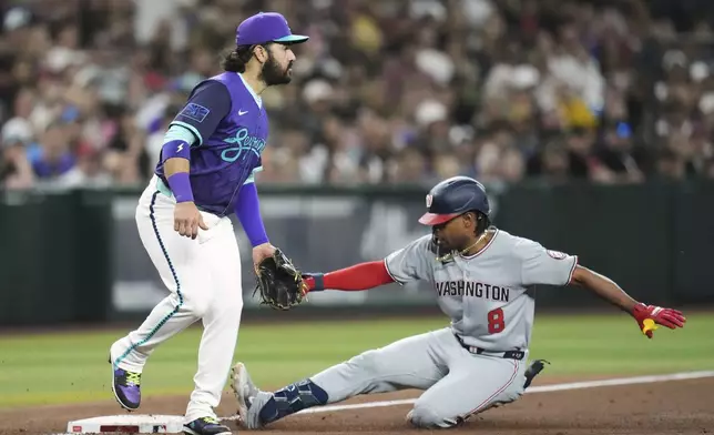 Washington Nationals' José Tena (8) slides safely into third base with a triple as Arizona Diamondbacks third baseman Eugenio Suárez waits for a possible throw during the third inning of a baseball game Friday, May 30, 2025, in Phoenix. (AP Photo/Ross D. Franklin)
