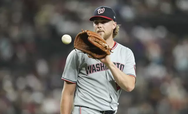 Washington Nationals starting pitcher Jake Irvin gets a news baseball during the third inning of a baseball game against the Arizona Diamondbacks Friday, May 30, 2025, in Phoenix. (AP Photo/Ross D. Franklin)