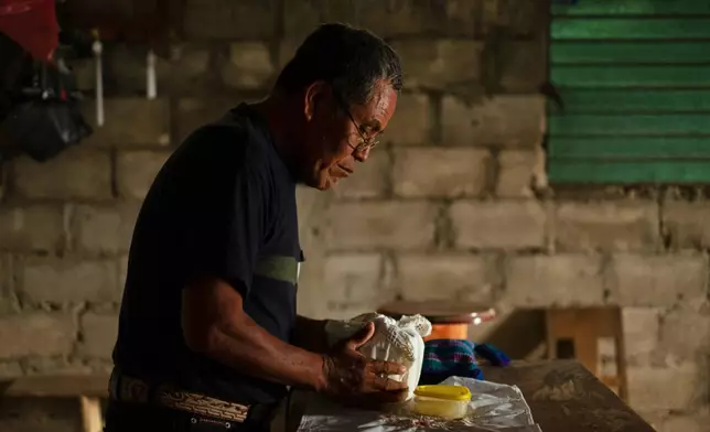 Deacon Juan Pérez Gómez prepares to unwrap Communion wafers consecrated by a priest, in the Simojovel municipality,, Mexico, Saturday, April 26, 2025. (AP Photo/Isabel Mateos)