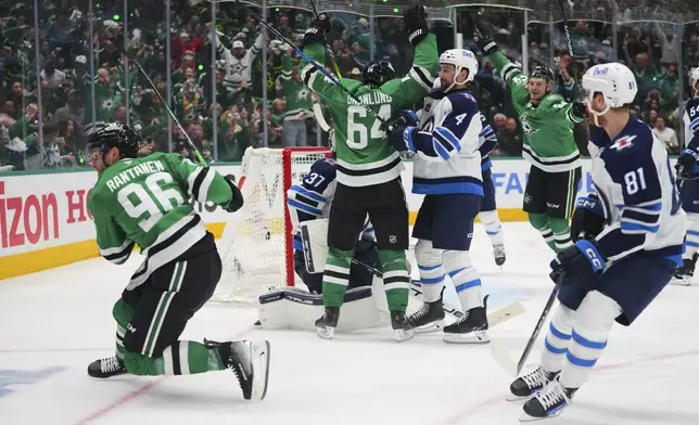 Dallas Stars' Mikko Rantanen (96), Mikael Granlund (64) and Roope Hintz, rear, celebrate Rantanen's goal as Winnipeg Jets' Neal Pionk (4) and Kyle Connor (81) look on in the third period of Game 3 of a second-round NHL hockey playoff series in Dallas, Sunday, May 11, 2025. (AP Photo/Julio Cortez)