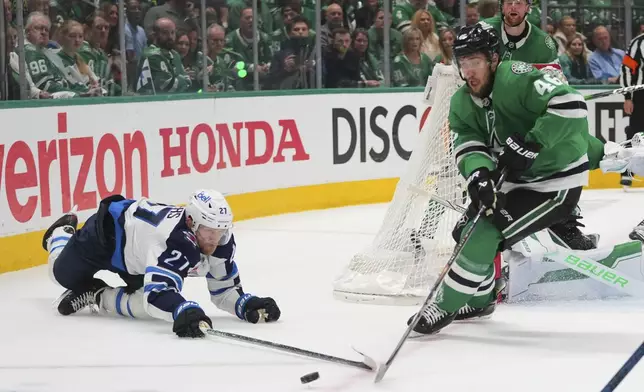 Winnipeg Jets' Nikolaj Ehlers (27) and Dallas Stars' Ilya Lyubushkin (46) work to control the puck in the second period of Game 3 of a second-round NHL hockey playoff series in Dallas, Sunday, May 11, 2025. (AP Photo/Julio Cortez)
