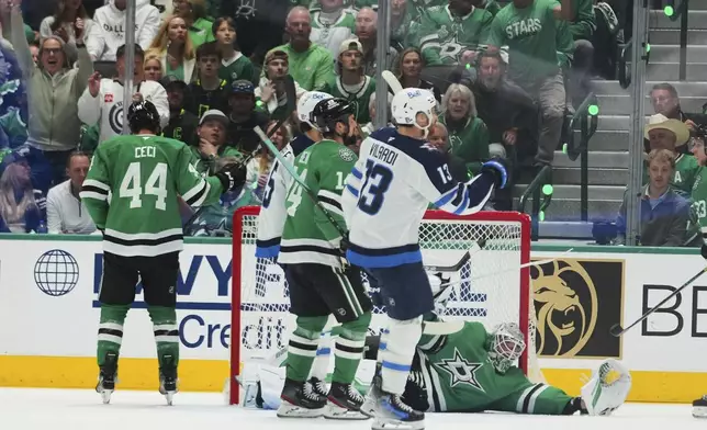 Winnipeg Jets' Gabriel Vilardi (13) celebrates a goal scored by Kyle Connor, standing nearby, as Dallas Stars goaltender Jake Oettinger (29) lies on the ice after the score in the first period of Game 3 of a second-round NHL hockey playoff series in Dallas, Sunday, May 11, 2025. (AP Photo/Julio Cortez)
