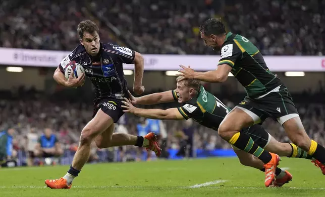 Union Bordeaux-Begles' Damian Penaud, left, avoids a tackle to go onto score a try during the Investec Champions Cup final between Northampton Saints and Bordeaux-Begles, at the Principality Stadium, Cardiff, Wales, Saturday May 24, 2025. (Andrew Matthews/PA via AP)