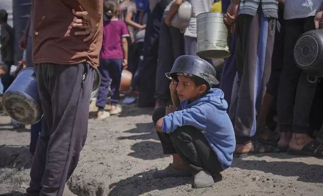 A boy holds an empty pot over his head as he waits for donated food at a community kitchen in Khan Younis, in the southern Gaza Strip, Friday, May 9, 2025. (AP Photo/Abdel Kareem Hana)