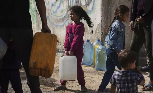 Palestinians collect water in jerrycans at a distribution point west of Gaza City, Sunday, May 11, 2025. (AP Photo/Jehad Alshrafi)