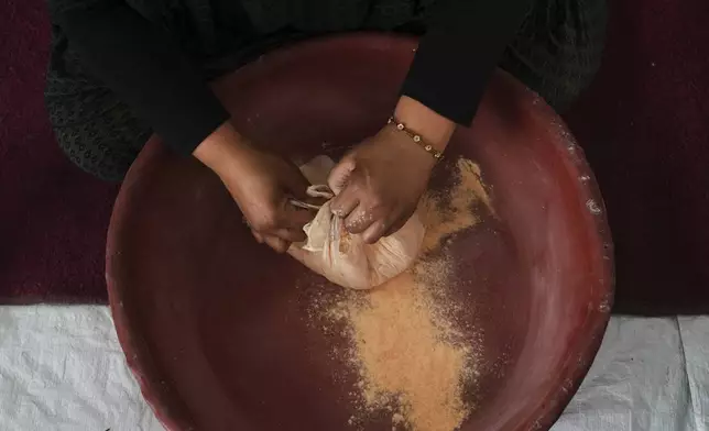 Nevin Qassim, a displaced Palestinian woman, prepares ground lentil dough as a substitute for bread due to a shortage of flour in the Gaza Strip, in Khan Younis, on Sunday, May 11, 2025. (AP Photo/Abdel Karem Hanna)