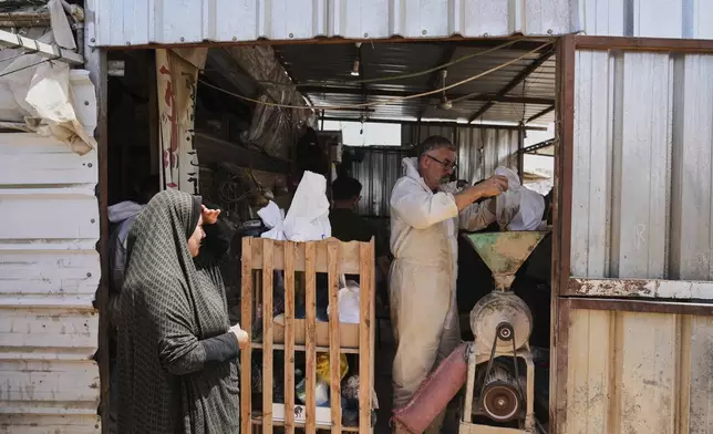 Nevin Qassim, a displaced Palestinian woman purchases ground lentils as a substitute for making bread due to a shortage of flour in the Gaza Strip, in Khan Younis, on Sunday, May 11, 2025. (AP Photo/Abdel Karem Hanna)
