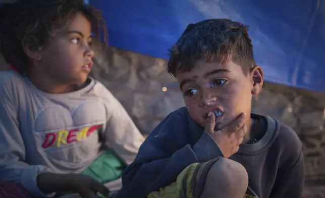 Raed Zaharna, right, and his sister Sally sit in their family tent after their mother, Ward, returned empty-handed from trying to receive donated food at a community kitchen in Khan Younis, in the southern Gaza Strip, Friday, May 9, 2025. (AP Photo/Abdel Kareem Hana)